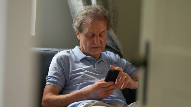 istock Candid old man using phone, senior person sitting on sofa looking at smartphone 1362530357