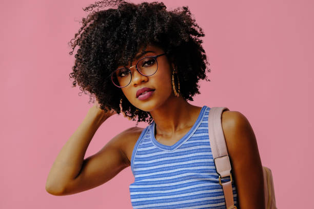 istock beautiful young female student in eyeglasses posing on pink background 1362530393