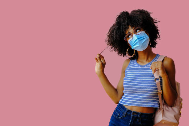 istock young female student with backpack wearing protective mask and posing on pink background, back to school concept 1362530446