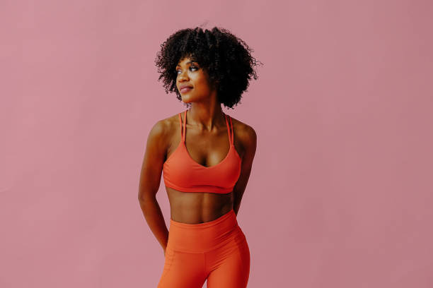 beautiful smiling young adult woman in sports outfit looking aside isolated on pink background - african descent american culture exercising women imagens e fotografias de stock