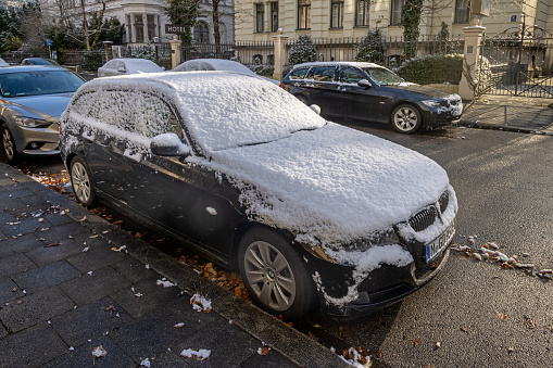 Car covered in light snow on a winter morning in the German city Munich, which is the capital city in Bavaria