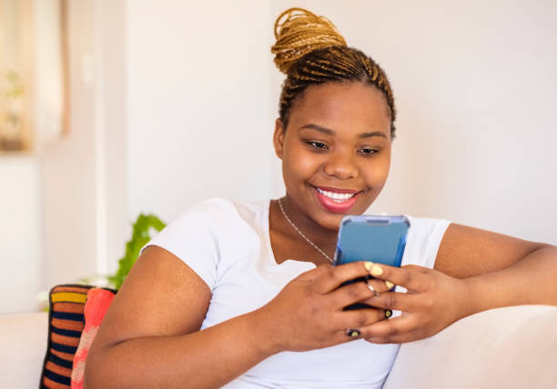 istock Smiling woman sitting at home using a smart phone 1362534221