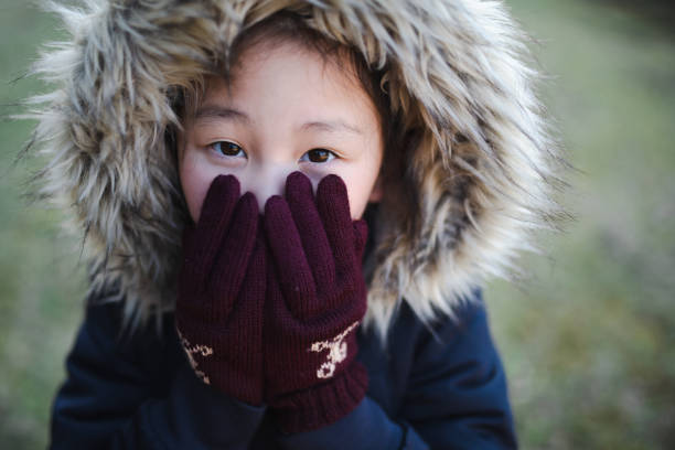 彼女の冷たい手に吹く女の子 - 防寒ウエア ストックフォトと画像