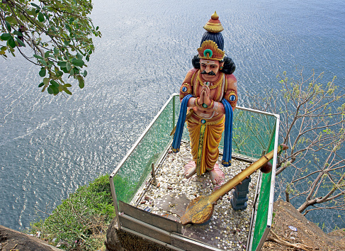 Hindu effigy overlooks the sea in a precarious position at Lovers Leap, Swami Rock, Koneswaram Temple, Trincomalee, Sri Lanka, South Asia. Sri Lanka, formerly Ceylon, is a  beautiful warm tropical island off the south eastern coast of India with a rich history of Sinhalese kingdoms and a mixture of faiths including Hindu Buddhist and Tamil as well as Dutch and British colonial influences. It has a wealth of birdlife and wildlife including many endangered wild animals.