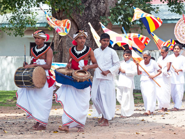 Buddhist devotional ceremony with Sinhalese drummers in traditional white ceremonial robes in procession along street in Polonnaruwa, Sri Lanka, South Asia. Sri Lanka, formerly Ceylon, is a  beautiful warm tropical island off the south eastern coast of India with a rich history of Sinhalese kingdoms and a mixture of faiths including Hindu Buddhist and Tamil as well as Dutch and British colonial influences. It has a wealth of birdlife and wildlife including many endangered wild animals.