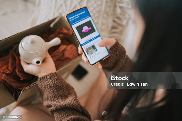 Unhappy Asian Chinese Woman Complaining Using Mobile App On Received Different Colour Teapot From Online Shopping A Living Room Stock Photo - Download Image Now