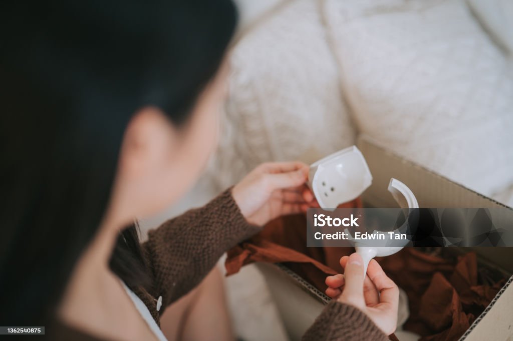 unhappy asian chinese woman holding broken ceramic teapot from online shopping a living room Broken Stock Photo