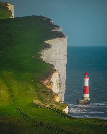 Famous 80 years red and white striped lighthouse was manned by three keepers, here on the chalk headland in East Sussex, England. It's a 500ft drop down those chalky cliffs