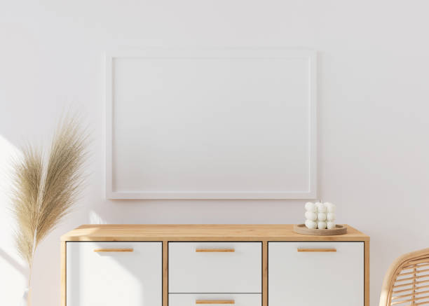 istock Empty picture frame on white wall in modern living room. Mock up interior in scandinavian, boho style. Close up view. Free space for your picture. Wooden console and pampas grass. 3D rendering. 1362542690