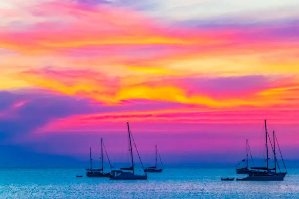 Yachts boats in front of the most beautiful colorful sunset at Tropical Paradise island Koh Phayam Ao Khao Kwai Beach in Ranong Thailand.