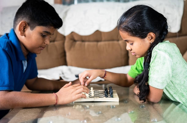 Focus on girl, concentrated Sibling Kids busy playing chess at home - concept of childhood mental development, gameplay and entertainment Focus on girl, concentrated Sibling Kids busy playing chess at home - concept of childhood mental development, gameplay and entertainment. sibling relatonship  in kids stock pictures, royalty-free photos & images