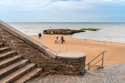 Arromanches, France - August 2, 2021: Stairs to the beach of with military artificial port from the world war and landing of allies in Arromanches Normandy, France