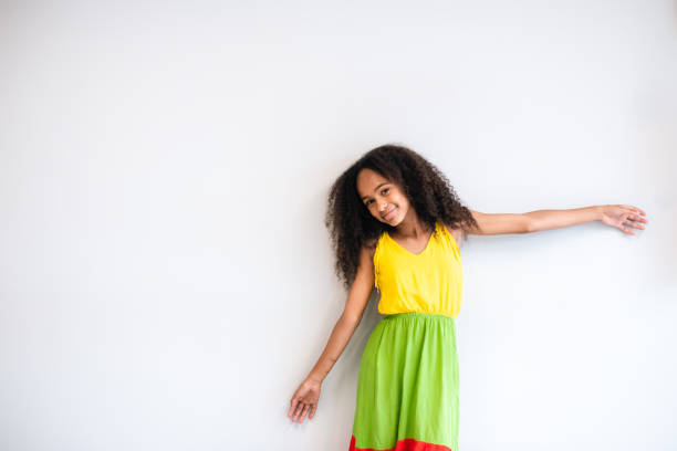 Charming young African American woman posing in stylish clothes on a purple backdrop, radiating happiness and beauty, perfect for fashion and lifestyle advertising.