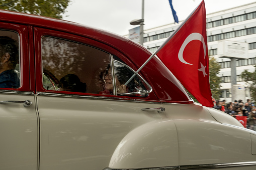Istanbul, Turkey - October 29, 2021: A woman holding turkish flag in window of old car for october 29 republic day. Editorial Shot in Istanbul Turkey. Editorial Shot in Istanbul Turkey.