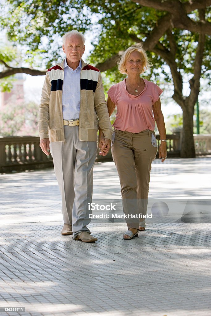 Pareja de ancianos caminando en el parque - Foto de stock de 55-59 años libre de derechos