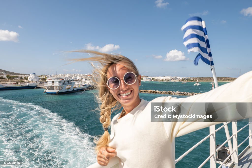 Young woman takes a selfie on a ferry in the greek islands View from the back of a ferry crossing from an island to another Greece Stock Photo