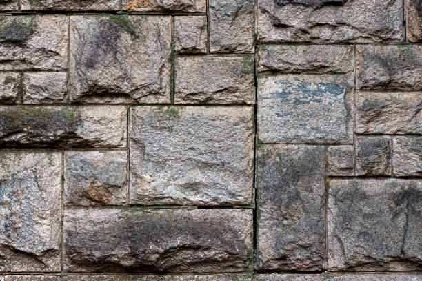 Old weathered wall made of granite stones, abstract background.