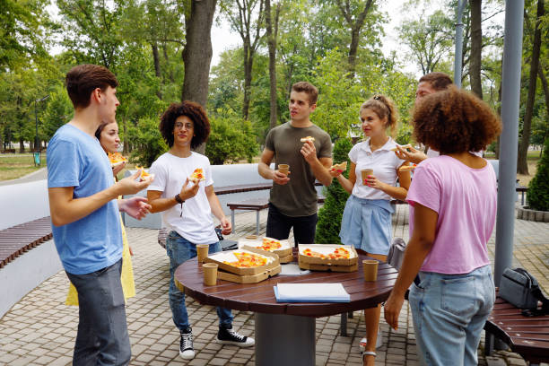 istock Friends eating pizza in park after classes 1362561311