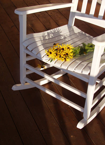 a white rocking chair with yellow flowers on the seat