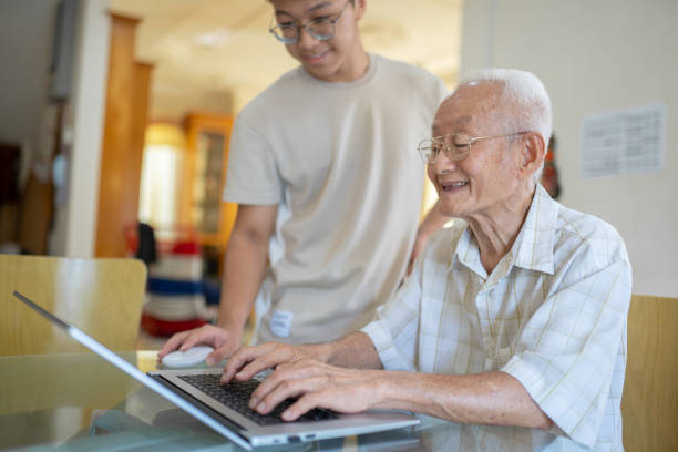 Asian Chinese grandfather learning internet teaching by grandchild at home. stock photo