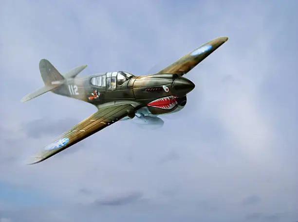 A World War 2 era P40E Warkawk flies out of the clouds. Compilation photo.