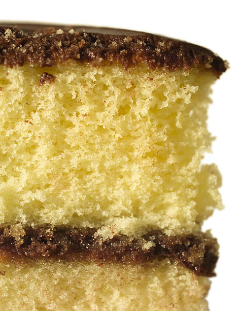 Close up photograph of a delicious vanilla cupcake with chocolate frosting. The cupcake paper is being pulled off and about to be eaten. The photograph is taken from the perspective of the person eating the cupcake. Focus is on the front portion of the cupcake and fades quickly.