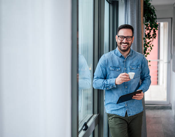 retrato de jovem adulto sorrindo empresário alegre em home office bebendo café da manhã rotina começando dia feliz bonito bem sucedido empresário freelancer verificando suas tarefas de negócios para o dia - cafe laptop espresso business - fotografias e filmes do acervo