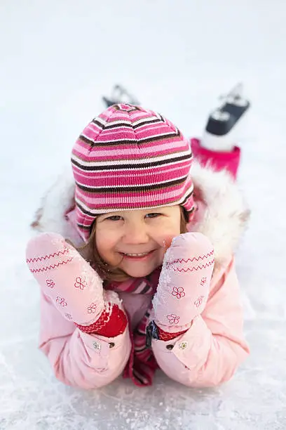 Photo of Young girl in pink posing on ice with ice skates on