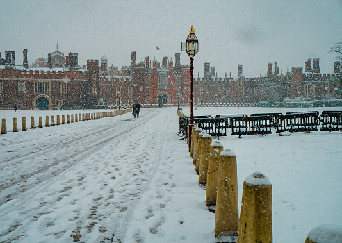 Couple walking under umbrella in Hampton Court Palace during snowfall