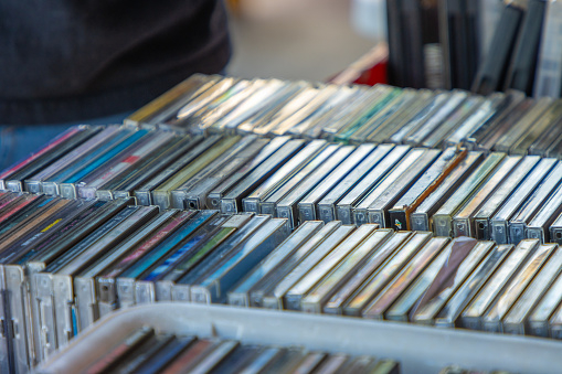 A stack of old music CDs on display outside a store.