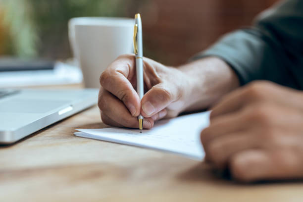 istock Hand of mature business man writing some notes in notebook while working with laptop  in the office. 1362576451
