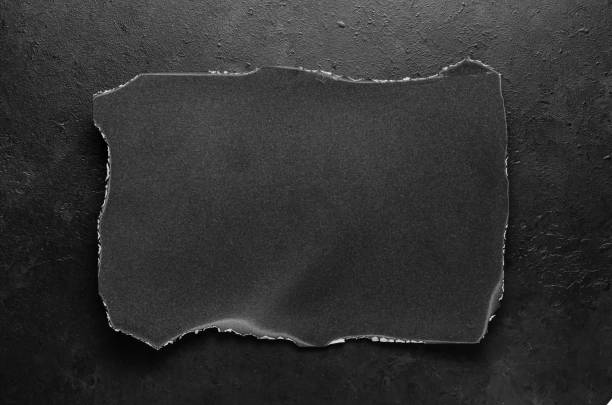 istock Black burnt paper on a dark concrete background. Design elements or portfolio. Copy space 1362578484