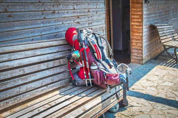 istock Large loaded backpack with walking sticks and water bottle and sleeping bag and child seat on wooden bench outside wooden bathrooms - hiking 1362582943