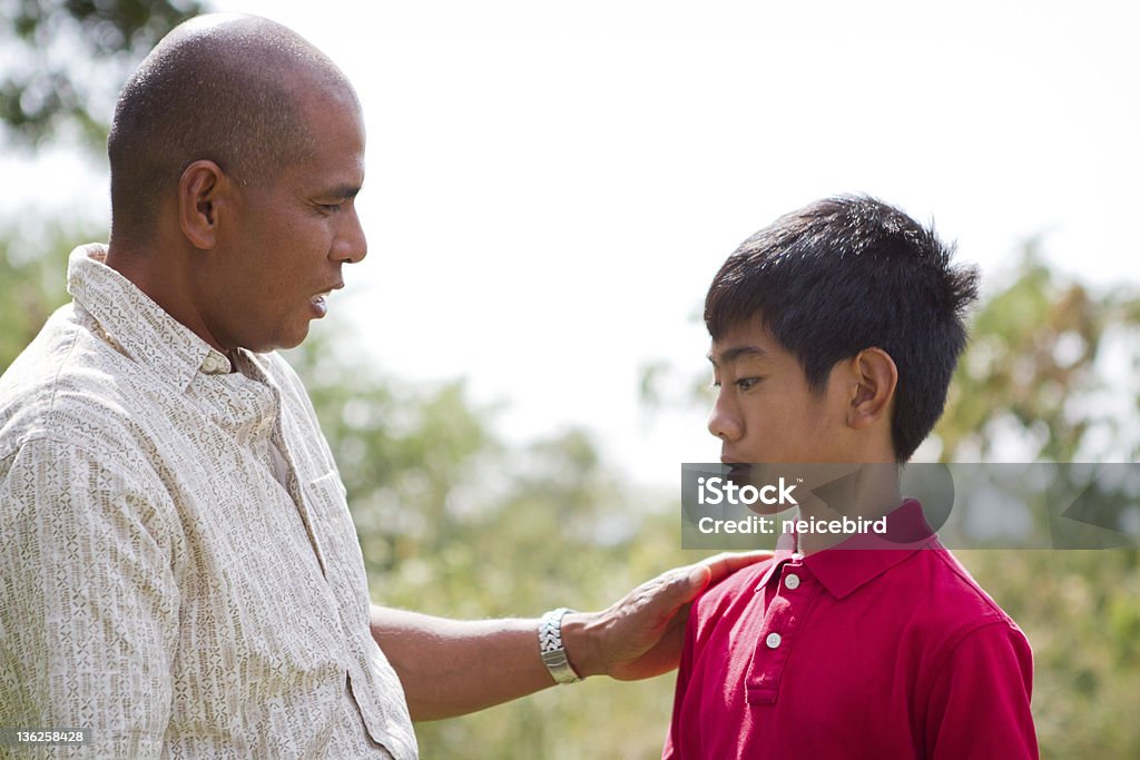 Father Talking To Son This father is having a talk with his son outside in the sunshine of Hawaii. Family Stock Photo