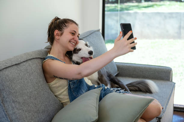 istock woman hugging her dog on the sofa and taking selfie 1362584518