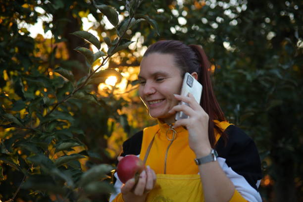 Young female farmer talking about apples and business over the phone