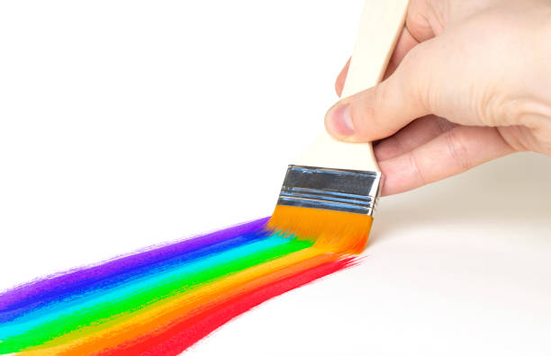 istock hand with a brush draws a rainbow on a white background. 1362585619