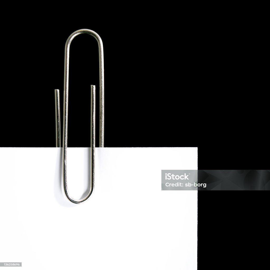 Paper clip Closeup view of paper clip and paper corner on a black background. Attached Stock Photo