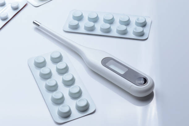istock tablets in a package and a white electronic thermometer on a white surface close-up. 1362590740