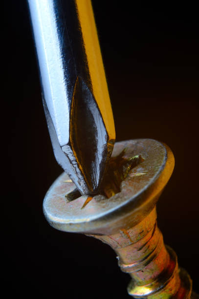 istock chrome screwdriver twists or unscrews the yellow self-tapping screw. close-up. 1362590746