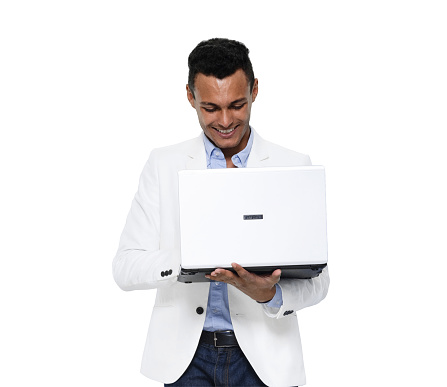 Front view of aged 20-29 years old with black hair african ethnicity young male standing in front of white background wearing blazer who is laughing who is working and using computer