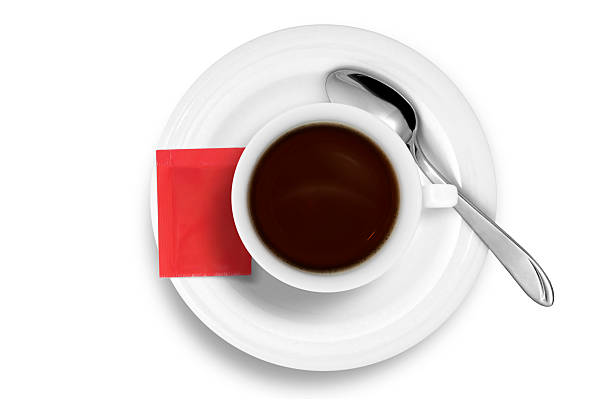Coffee Cup with Spoon and red sugar bag isolated on white, photographed in studio.