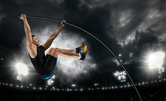 Professional pole vaulter training at the stadium in the evening. Sports banner. Horizontal copy space background