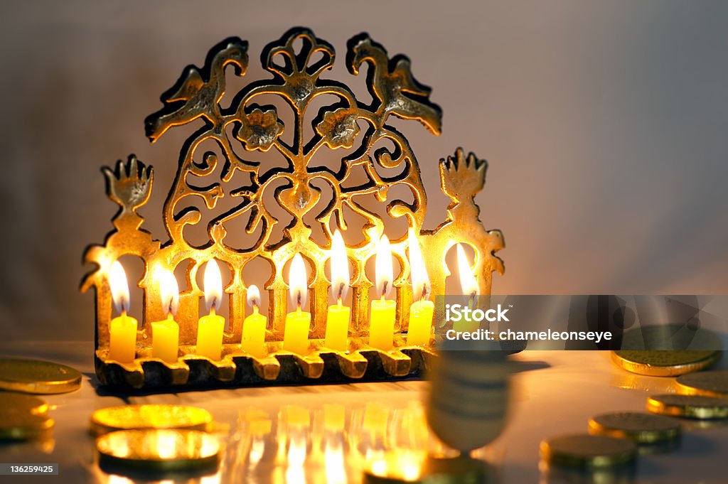 Jewish Holiday Hanukkah Photo of a dreidel (spinning top), gelts (candy coins) and an ancient brass menorah for the Jewish holiday of Hanukkah. Burning Stock Photo