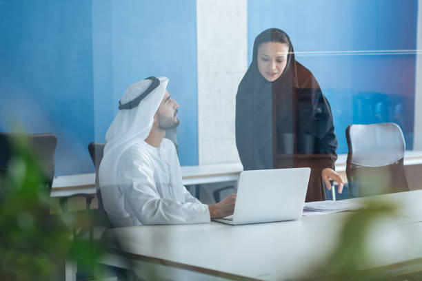 Handsome man and woman with traditional clothes working in an office of Dubai stock photo