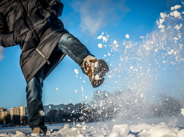 istock A man with a foot in a winter boot kicks the snow. 1362595376