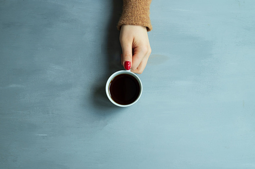 Girl holding a cup of coffee with red nail polish