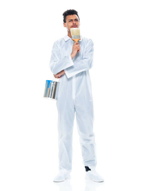 African ethnicity male house painter standing in front of white background wearing coveralls stock photo