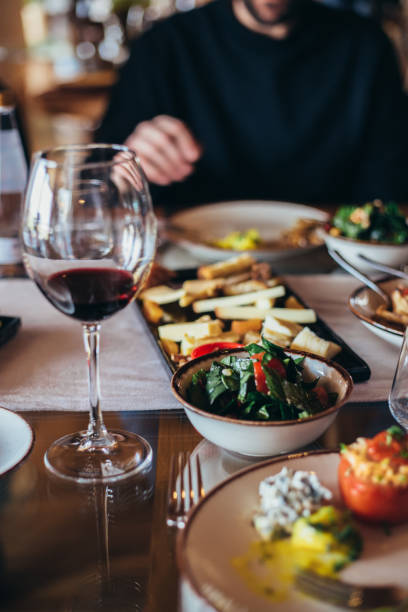 man sitting at a table with salad cheese and wineglass,food and drinks served on table - italian appetizer imagens e fotografias de stock