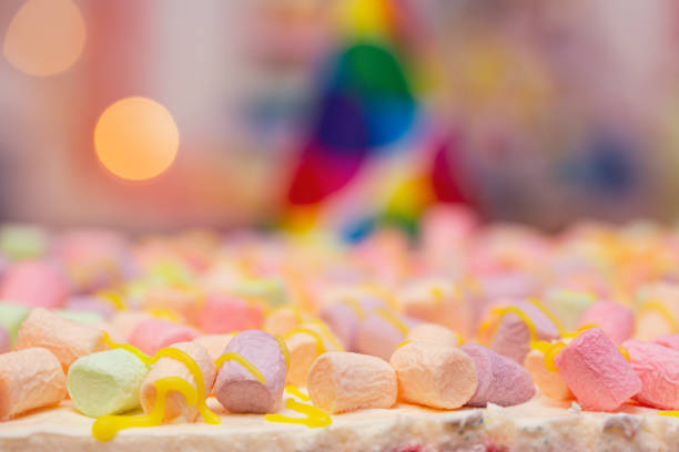 istock Concept of holiday or birthday. Multicolor five layer cake with colored marshmallow on the top and defocused lights as background 1362599696